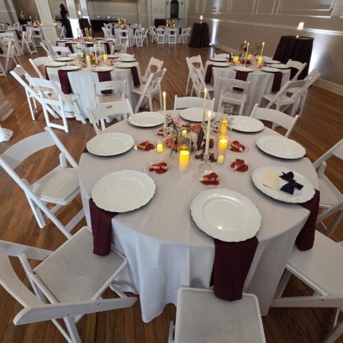 Close up image of a table set with chairs, plates, and candles